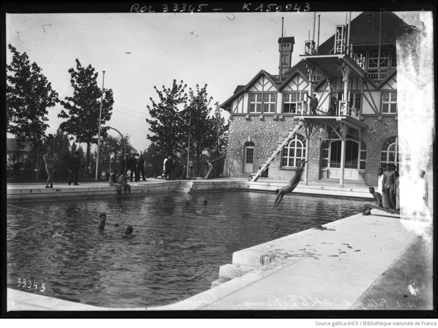 Un nageur plonge dans la piscine du Collège d’athlètes de Reims, devant le pavillon à colombages, en 1913